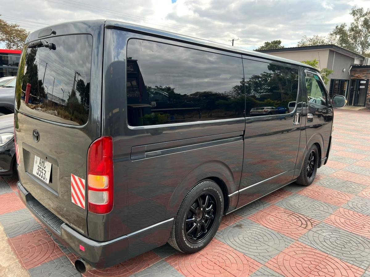 Rear three-quarter view of the charcoal Toyota Hiace, showing the tailgate and side glazing
