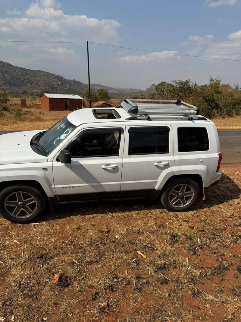 Side profile of the white Jeep Patriot showing the full-length roof carrier